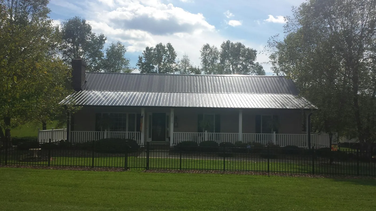 Gray metal roof on a brick ranch with a full width front porch — Gutter Guard Installation work by our crew in Kirkwood