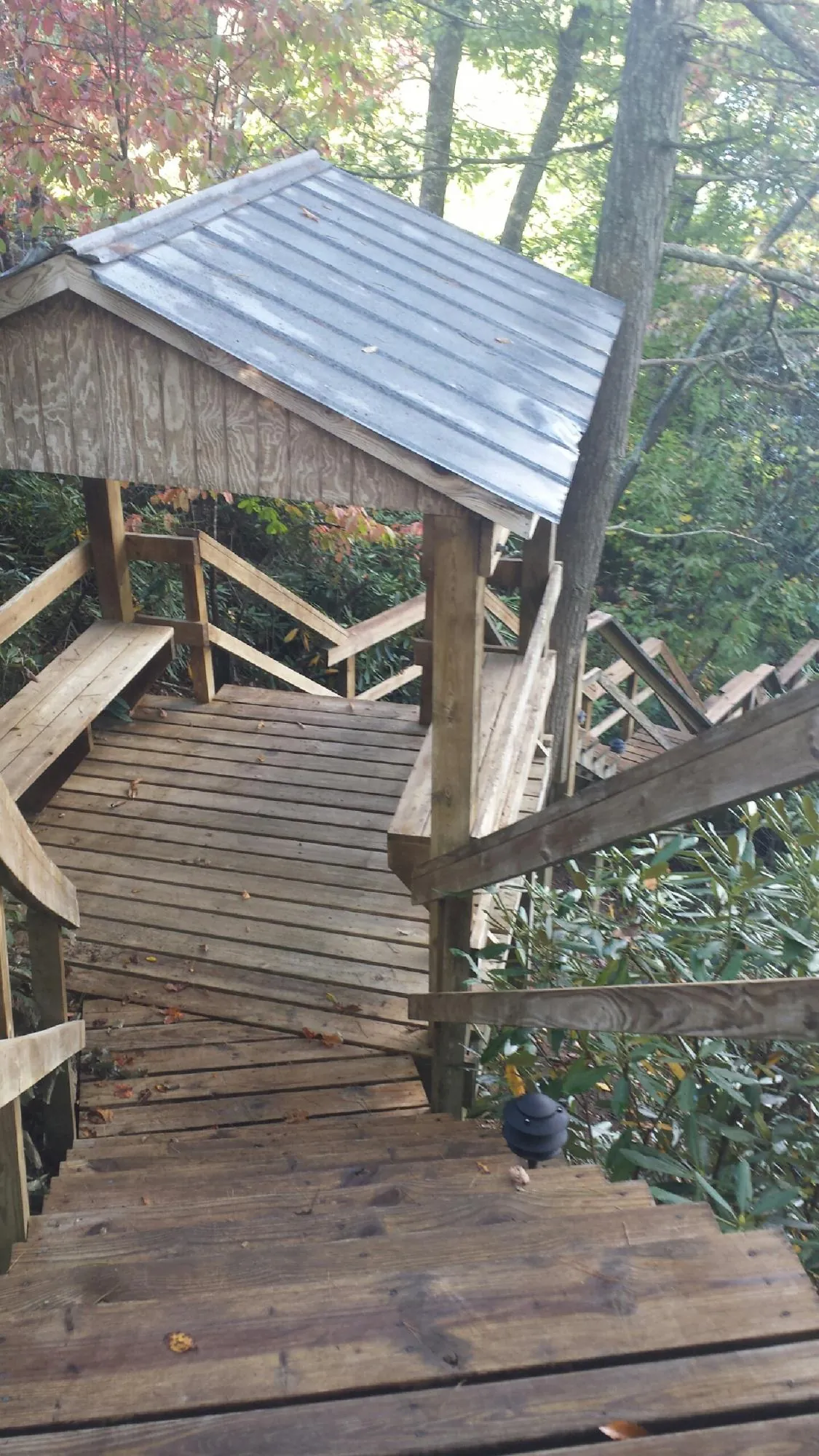 Metal roofed shelter over wooden steps on a wooded walkway — Skylight Repair & Installation work by our crew in Kirkwood