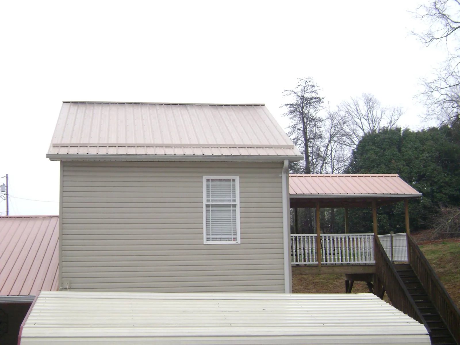 Tan metal roofs on a two story addition and attached porch, from a Roof Replacement job in Kirkwood
