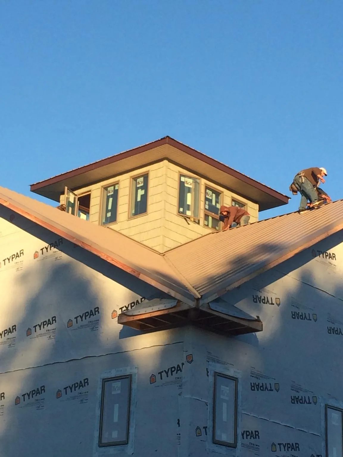 Roofers working around a rooftop cupola on a new metal roof at sunset — Roof Waterproofing in Kirkwood by Roofing Brothers